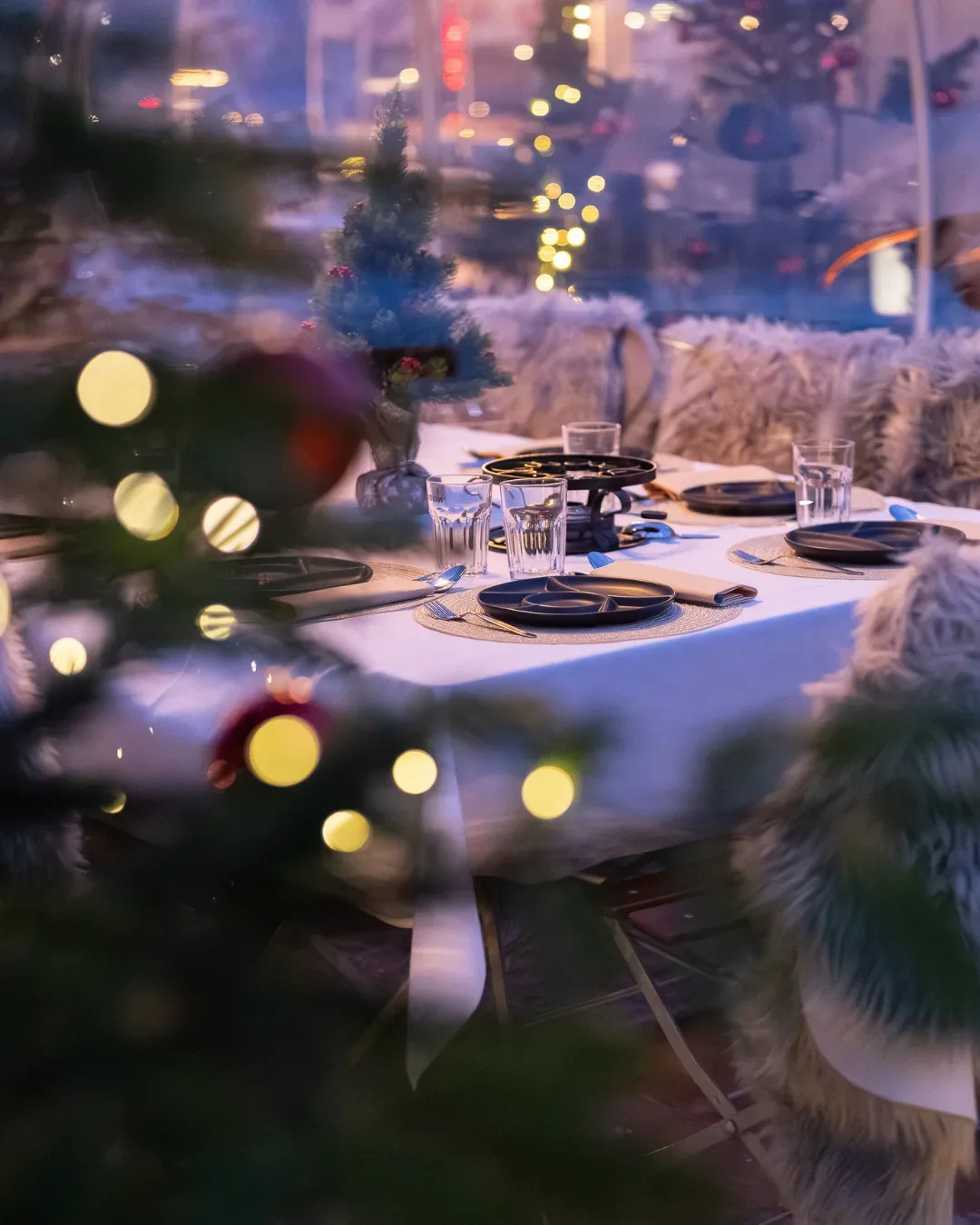 Festlich gedeckte Tafel für ein Weihnachtsessen hinter geschmücktem Christbaum