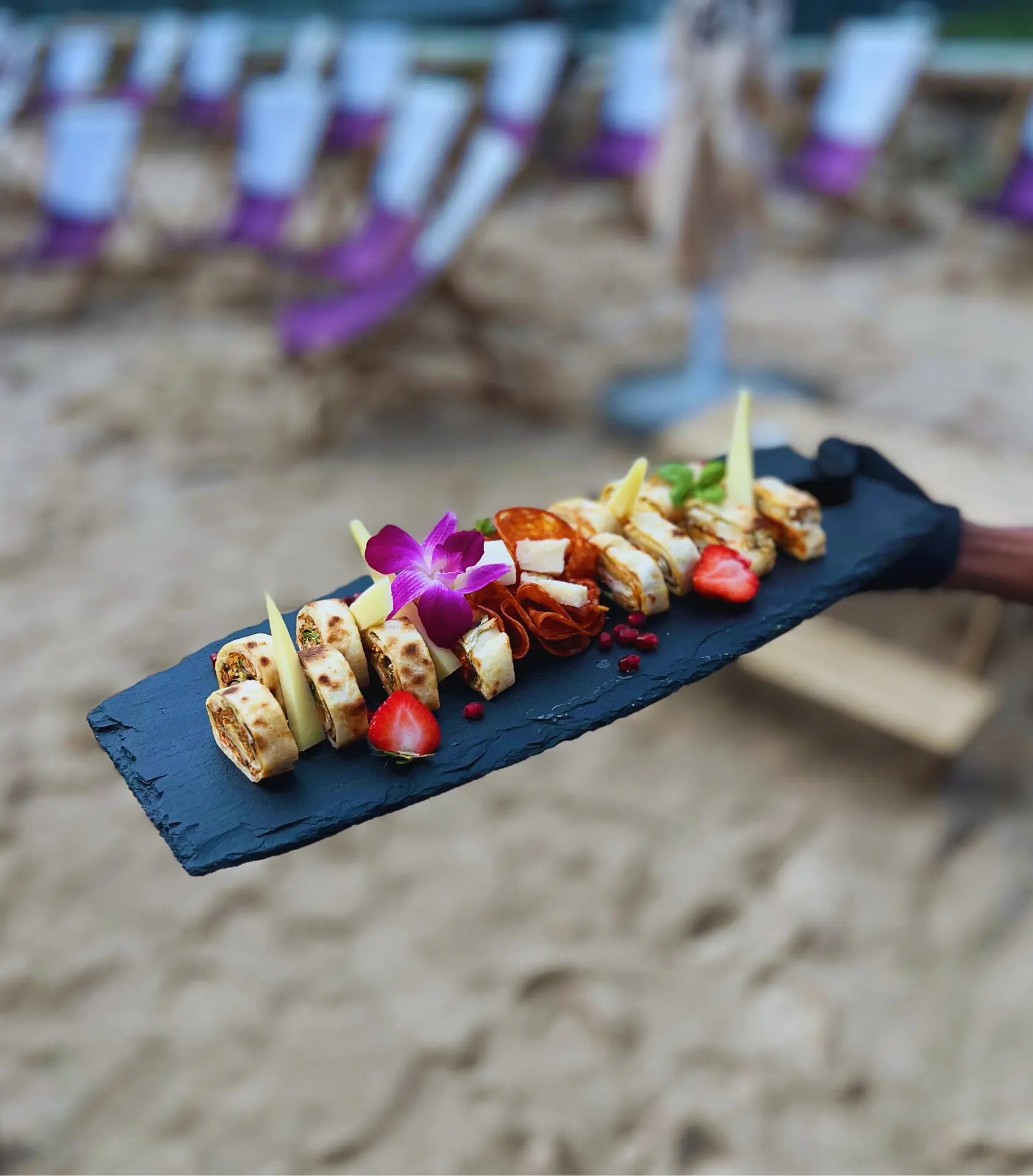 Apéro-Platte mit Wraps, Käse und Trockenfleisch auf schwarzer Schieferplatte