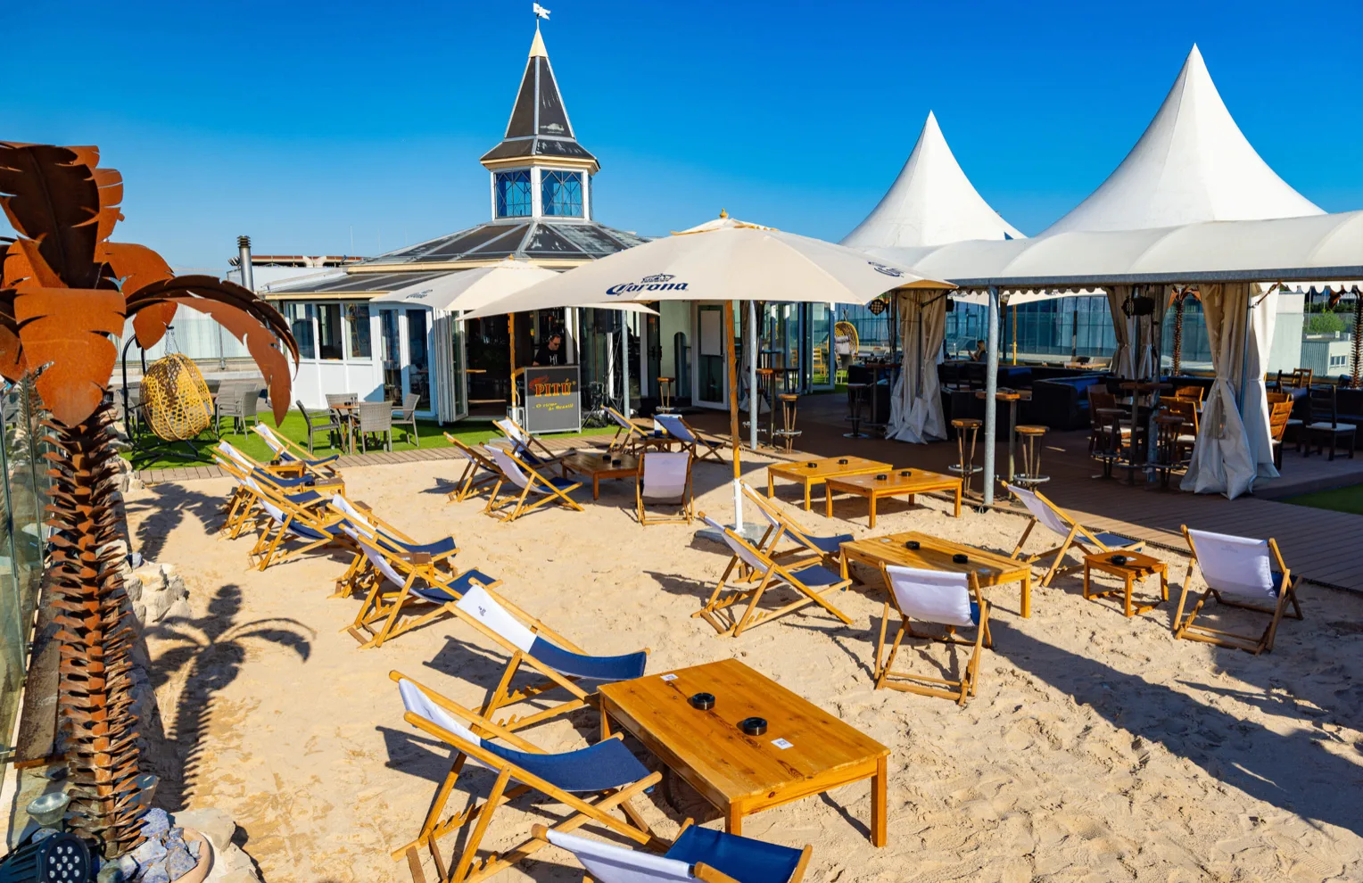 Gesamtansicht der Rooftop Beach-Oase mit Sand und Liegestühlen