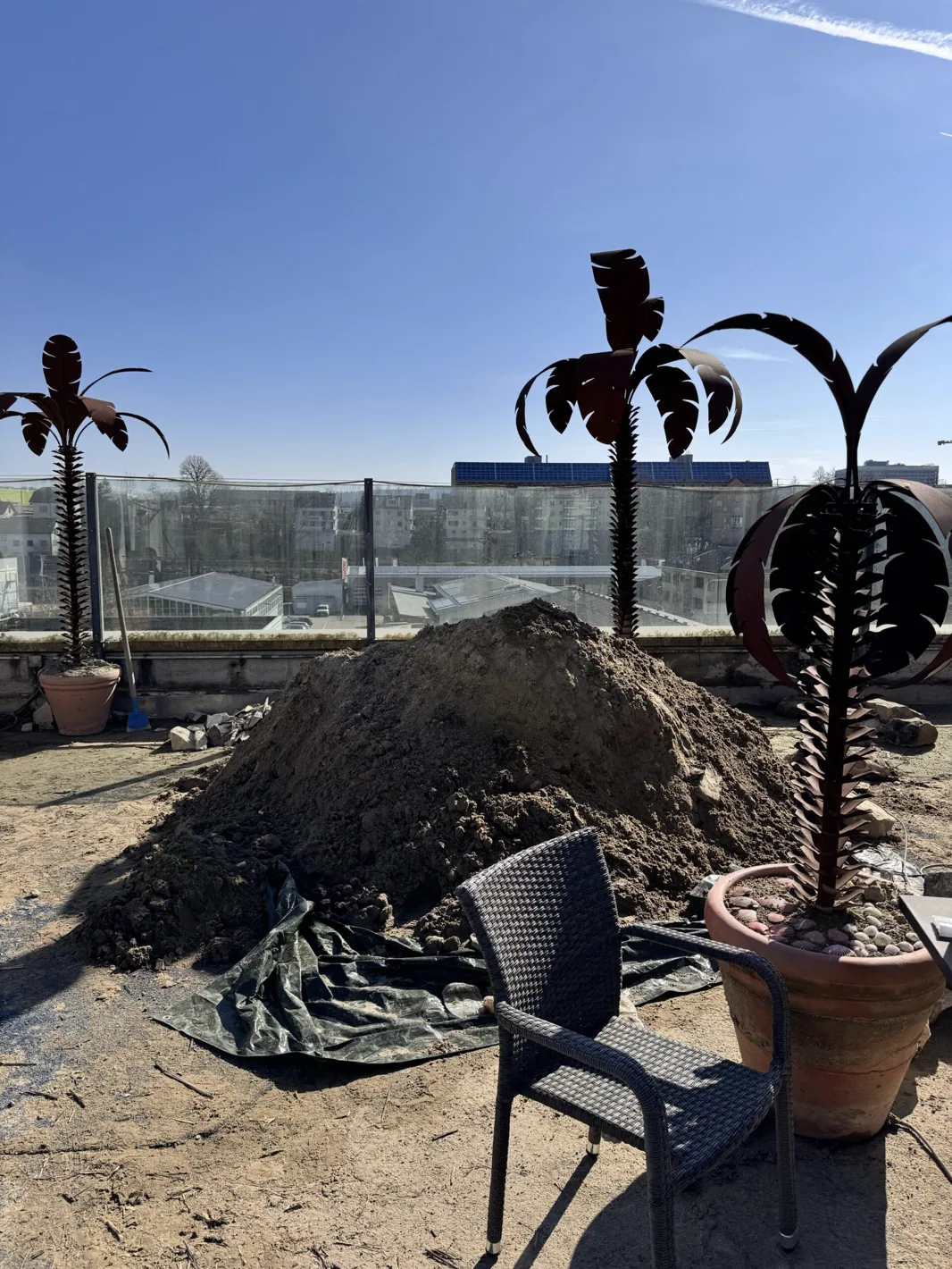 Erdhügel mit Metallpalmen und Stuhl auf der Rooftop Baustelle